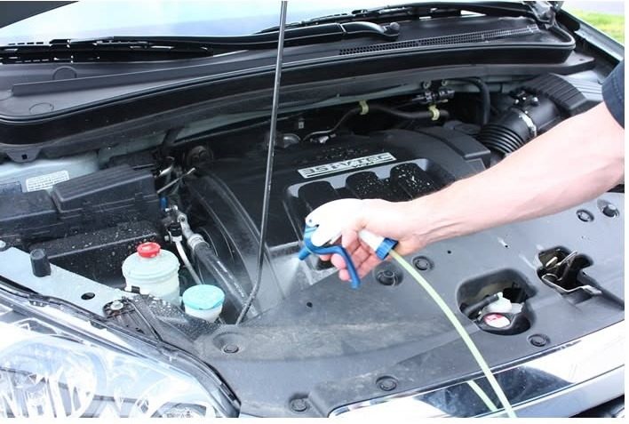 Rociando desengrasante en el motor con las manos: lavado de motor a domicilio