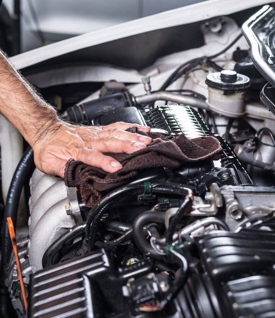 Mano limpiando el motor con un paño de microfibra