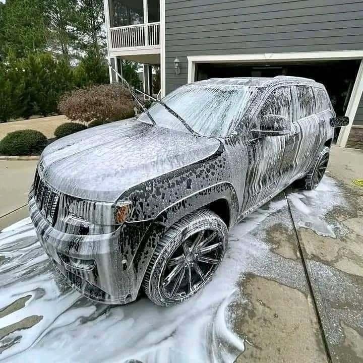 SUV Grand Cherokee cubierta de espuma en la entrada de una casa: servicio de lavado de autos a domicilio