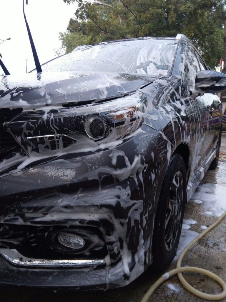 SUV gris con espuma y manguera en el piso